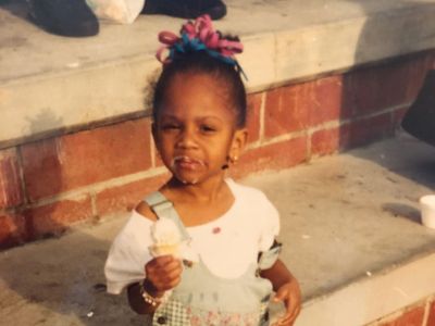 Geffri Hightower is holding an ice cream cone as their is cream all over her face.